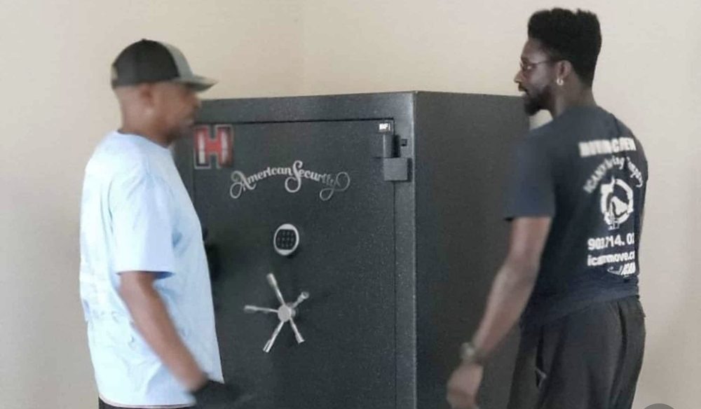 Two ICANN movers positioning an American Security gun safe against a wall