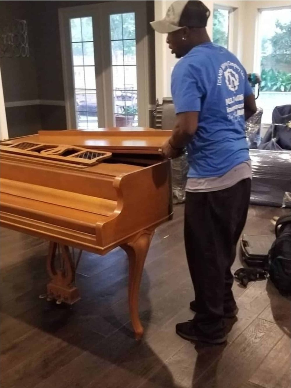 Two ICANN movers carrying an antique upright piano out of a house
